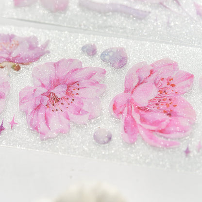 Macro close-up of Cherry Blossom Glitter Sand PET die-cut tape with textured glitter grain and delicate pink sakura petals on white background