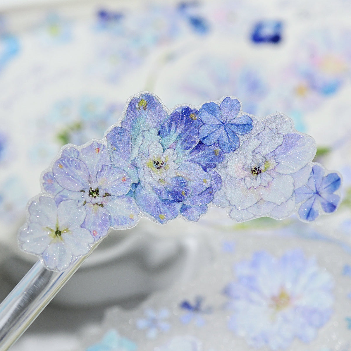 Handheld close-up of Kaleidoscope Shimmering Blue Glitter Sand PET die-cut tape with blue floral motifs and sparkling grain detail