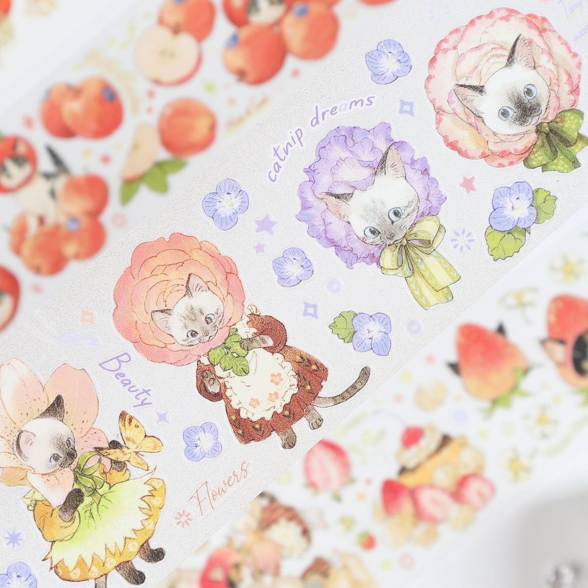 Handheld macro of Watercolor Cute Kittens Sweet Orchard Wildflower Fairy PET tape with soft dusty rose watercolor kitten illustrations, orchard fruits and wildflower fairy motifs, sparkling glitter texture and journal elements styled in the background