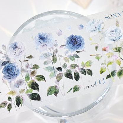 Macro close-up of Wilderness Rose Glacial Blue Glitter Sand PET die-cut tape with textured glitter grain and layered blue rose petals