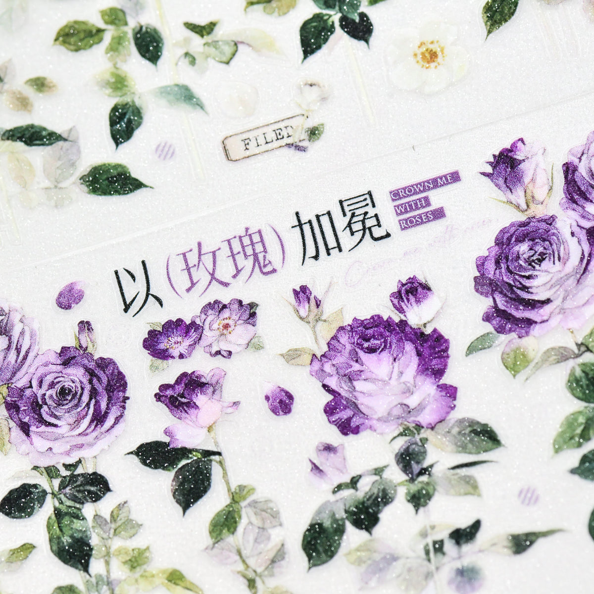 Close-up of Wilderness Rose Glacial Purple Glitter Sand PET tape die-cut edges with glitter texture and violet flower silhouette on white background
